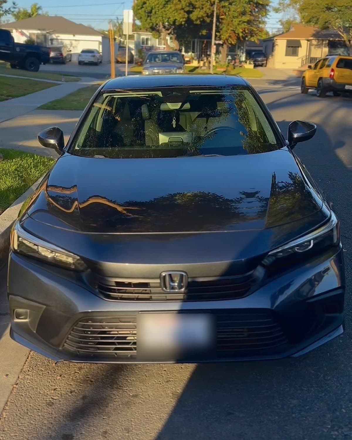 The same grey Honda Civic after detailing, hood glossy and mirror-reflective